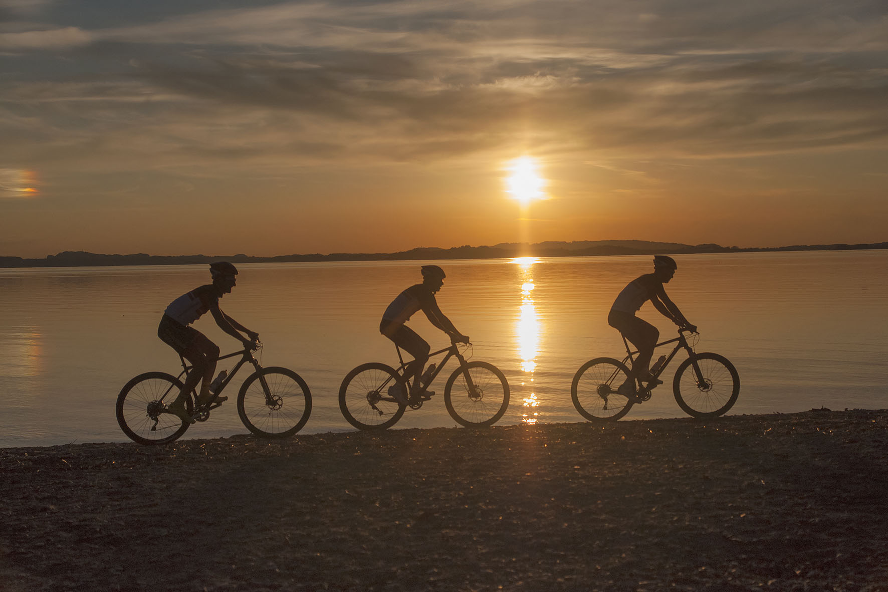 mountainbiker im sonnenuntergang am chiemseestrand in feldwies